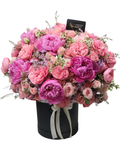 Bouquet of pink and purple flowers in a black box with a visible brand label.