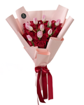 Bouquet of red and pink roses wrapped in pink paper with a red ribbon on a white background