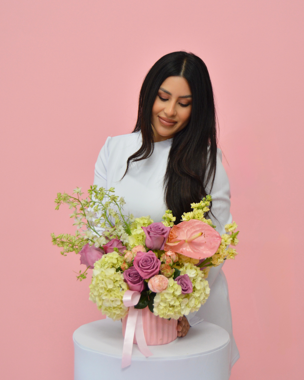 Woman holding a bouquet of flowers against a pink background