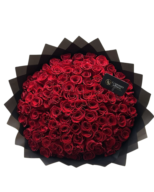 Bouquet of red roses in a black box with a visible brand label on a white background