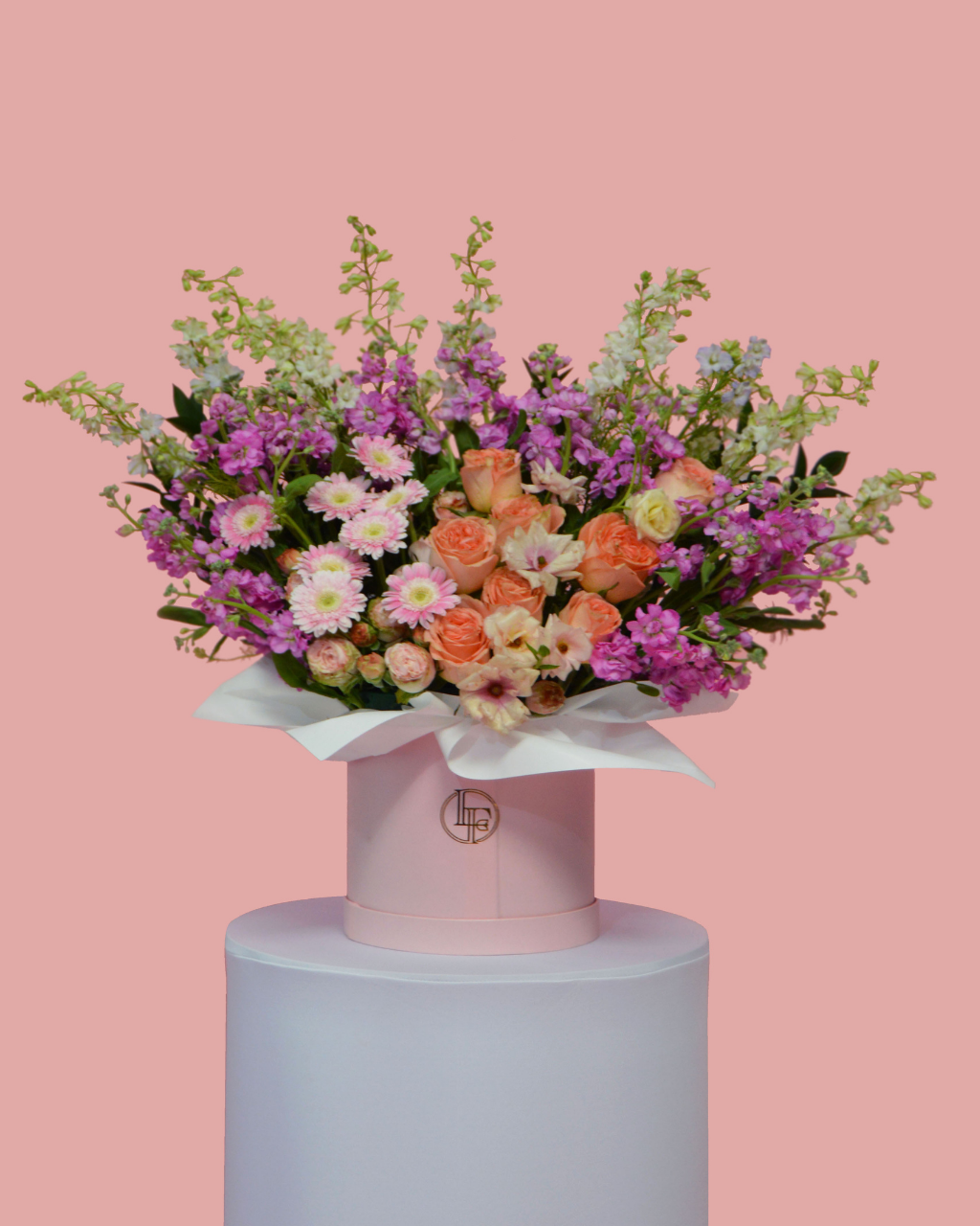 Colorful bouquet of flowers on a pink pedestal against a pink background
