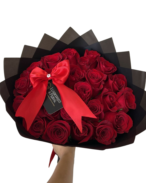Bouquet of red roses with a red bow and a visible brand tag on a white background