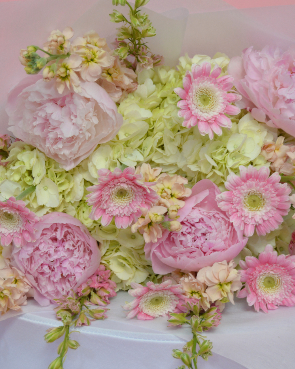 Assorted pink and green flowers in a decorative arrangement.