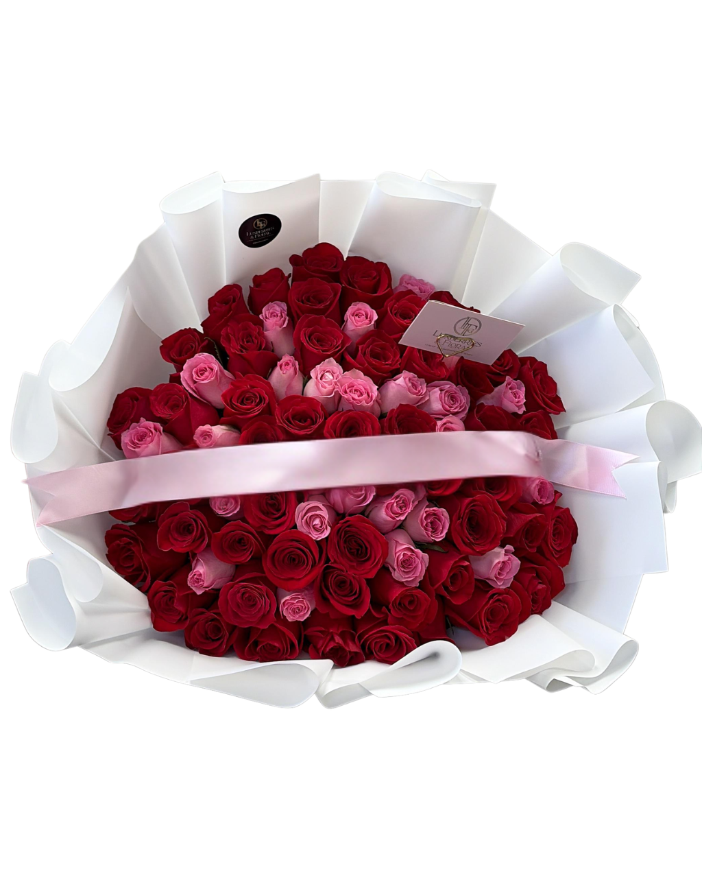Heart-shaped arrangement of red and pink roses in a white paper wrap with a pink ribbon on a white background.