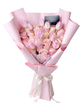 Bouquet of pink and white flowers wrapped in pink paper with a card on a white background