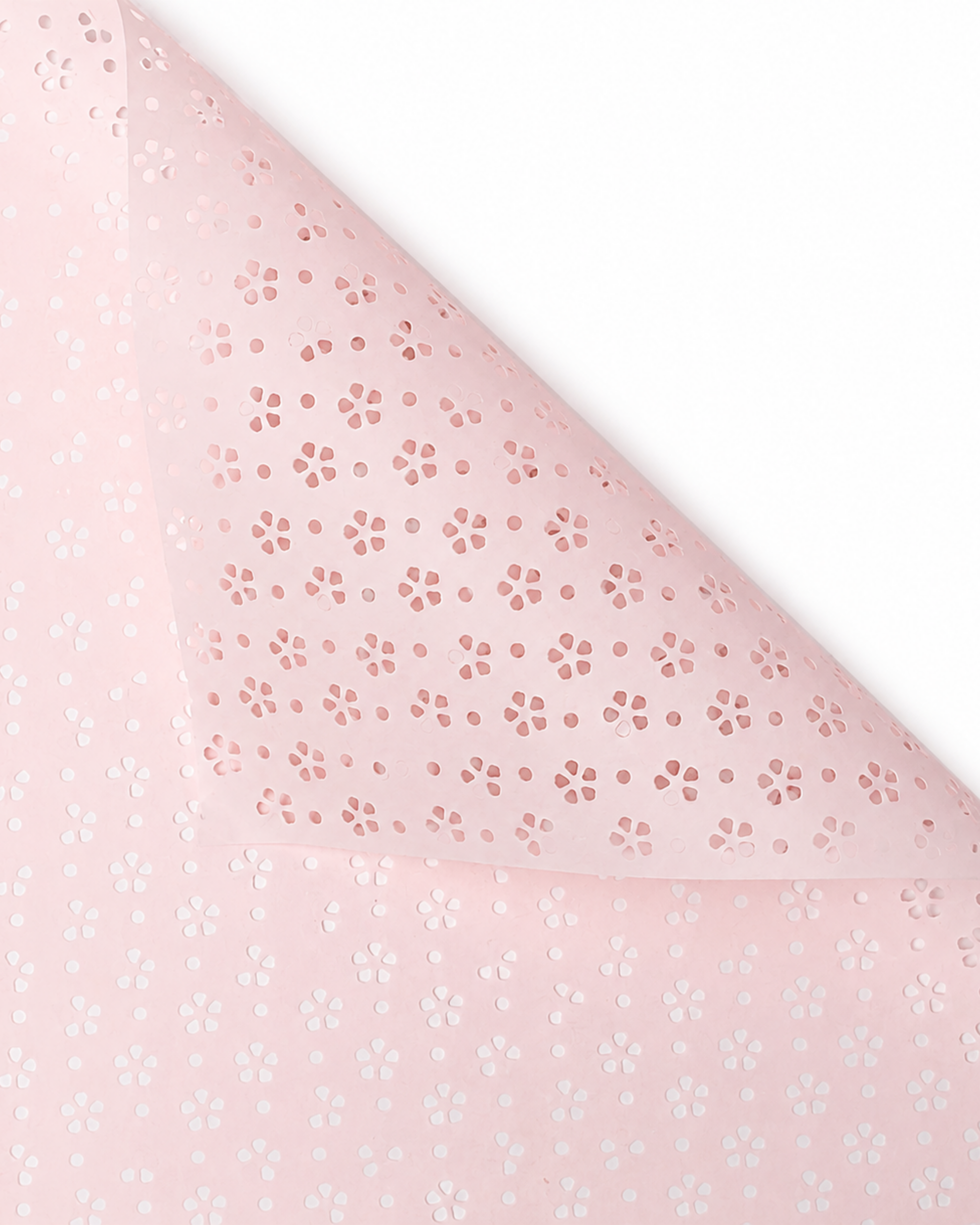 A close-up of a light pink sheet or fabric with a repeating small floral pattern, folded over on a white background to show both sides.