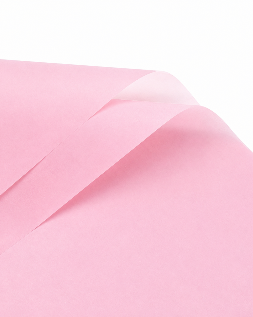A close-up of a light pink sheet of paper with soft folds and a slightly translucent quality, set against a clean white background.