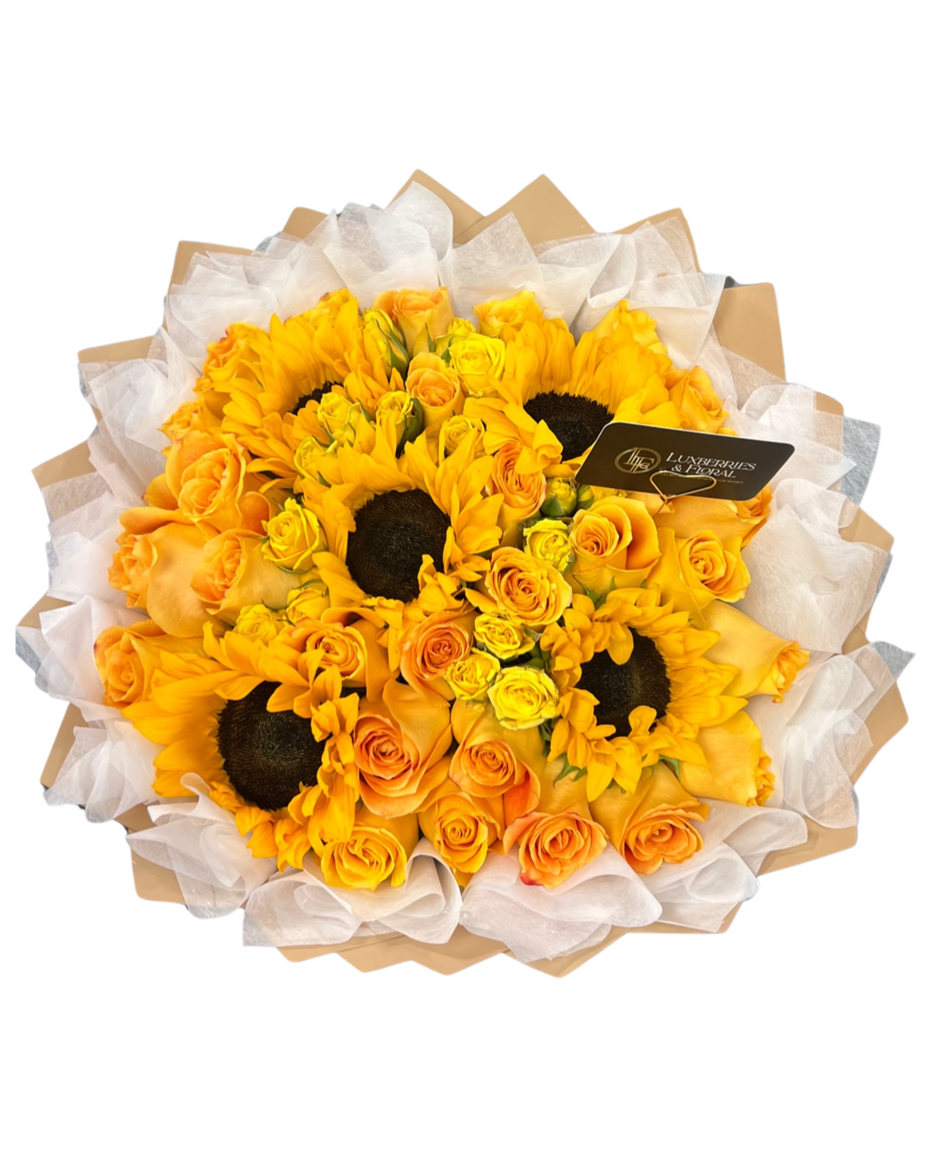 A round floral bouquet featuring yellow and orange sunflowers mixed with yellow roses, wrapped in white tissue paper and kraft paper, with a small black brand tag attached.