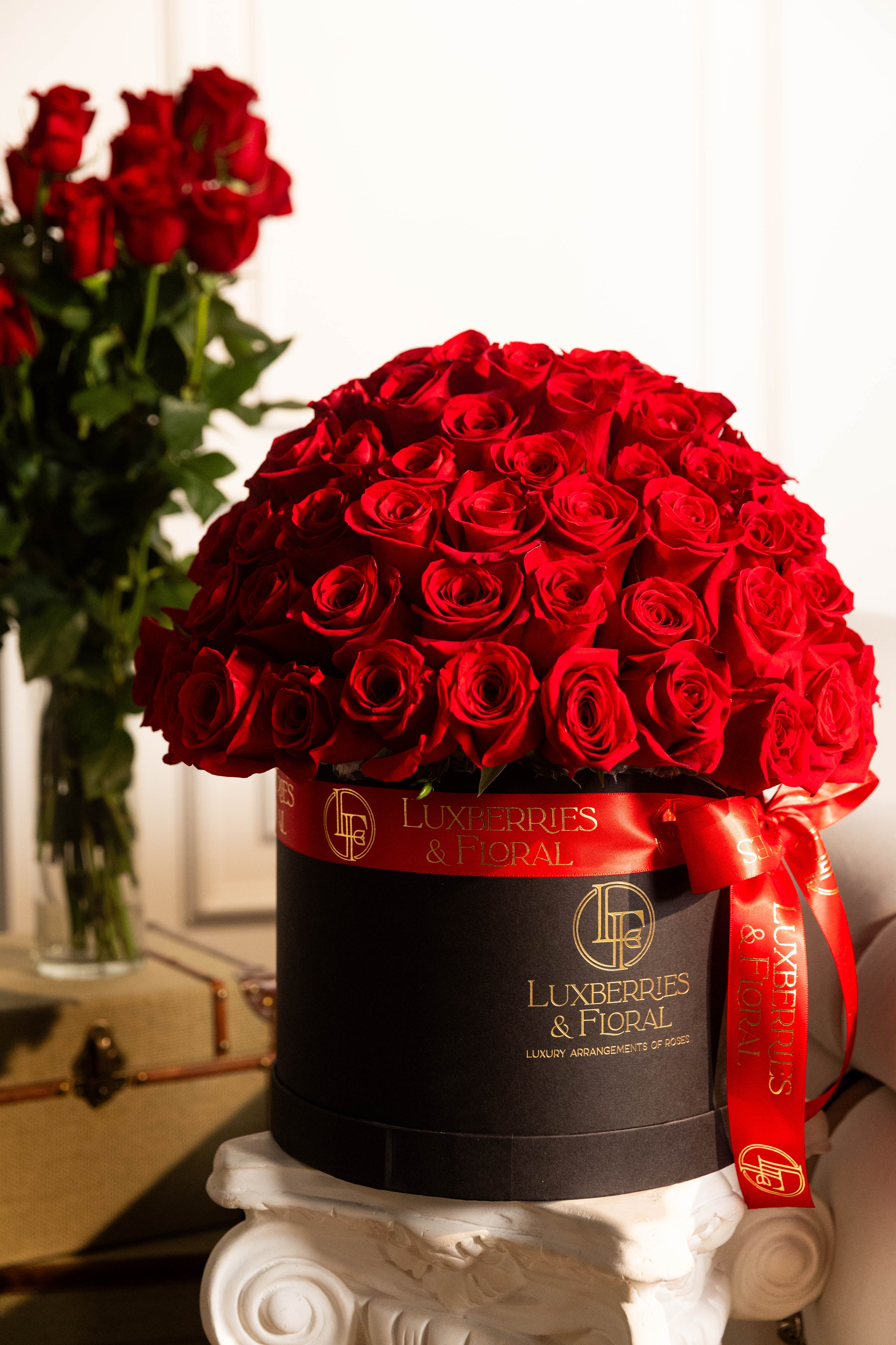 Black box filled with red roses and a visible brand logo on a white surface.