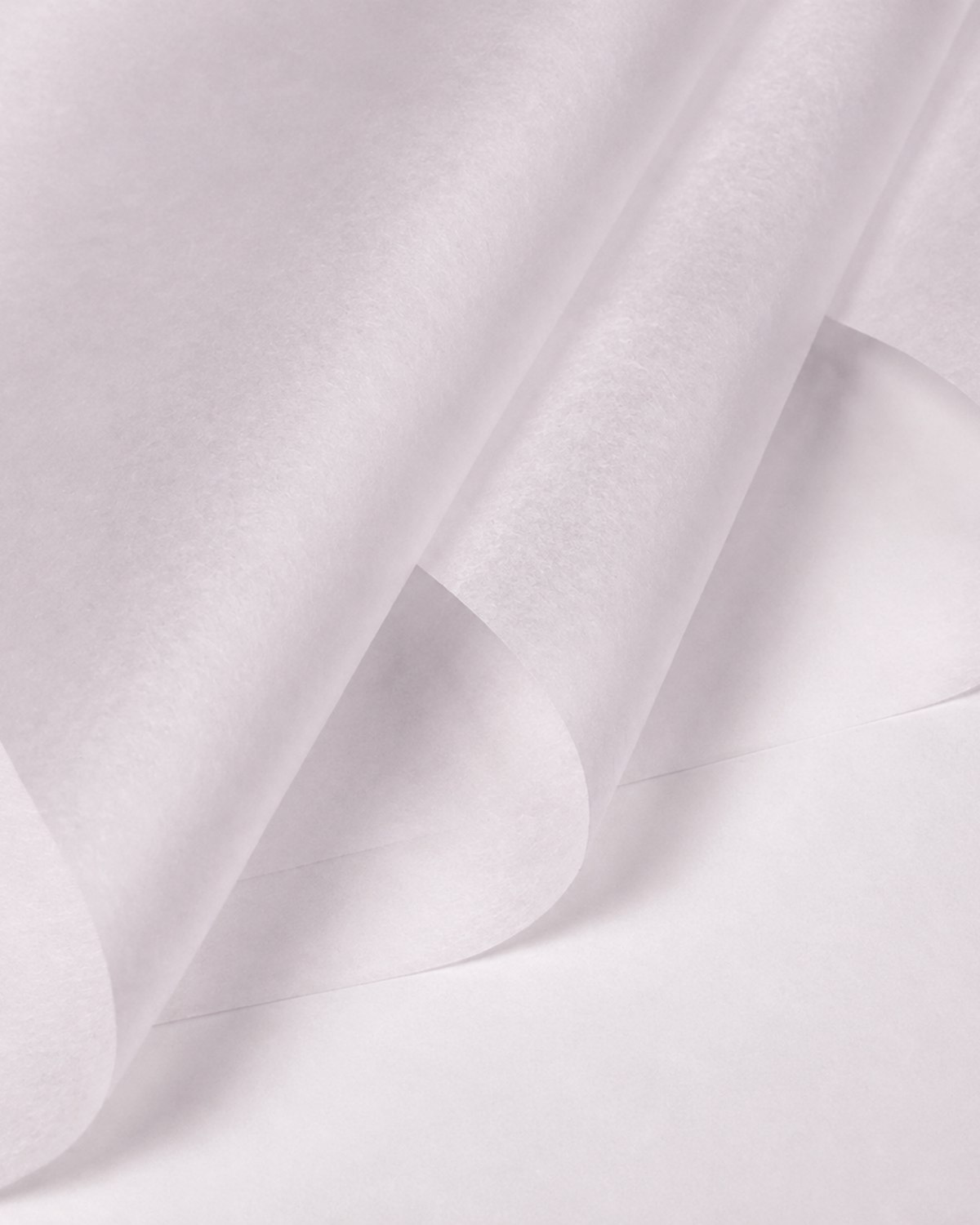 A close-up of a white semi-transparent sheet material, possibly parchment paper or wax paper, shown with soft folds and shadows.